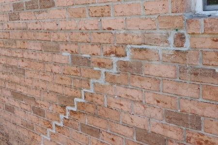 Close-up view of a brick wall with a prominent zigzag crack repair by MDH Foundation Repair.